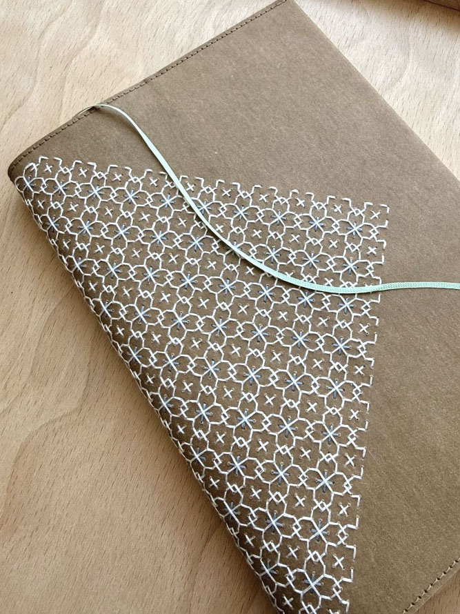 Hand-stitched geometric pattern on a tan notebook cover